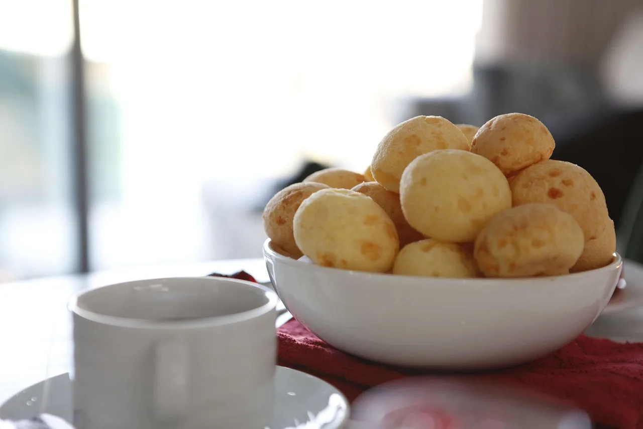 Pães de queijo em tigela ao lado de xícara de café